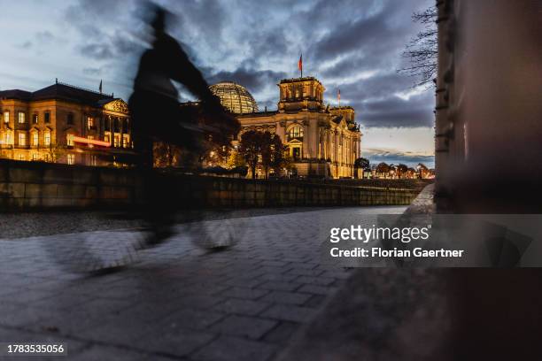 Cyclist is pictured in front of the German Bundestag during blue hour on November 15, 2023 in Berlin, Germany.