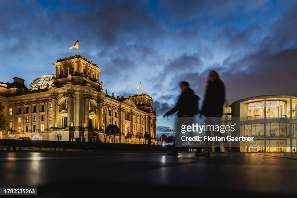 Two people are pictured in front of the German Bundestag during blue hour on November 15, 2023 in Berlin, Germany.