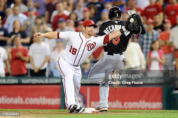 Adeiny Hechavarria of the Miami Marlins is safe at first base in the ninth inning ahead of the throw to Chad Tracy of the Washington Nationals at...
