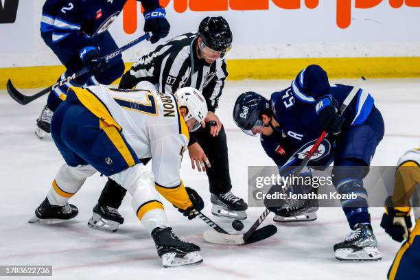 Michael McCarron of the Nashville Predators and Mark Scheifele of the Winnipeg Jets take a third period face-off at Canada Life Centre on November...