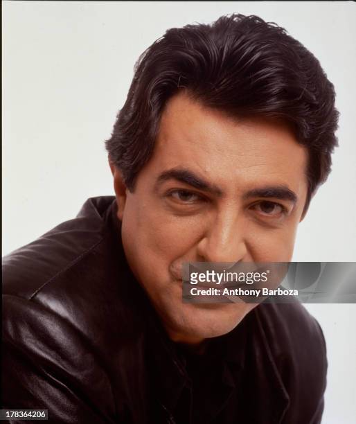 Portrait of American actor Joe Mantegna as he poses, dressed in a leather jacket, against a white background, 1991.