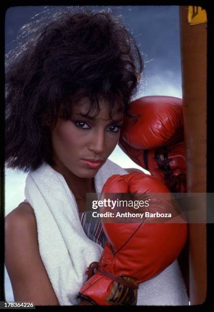 Portrait of fashion model Sheila Johnson as she poses in boxing gloves, with a towel over her shoulders, early 1980s.