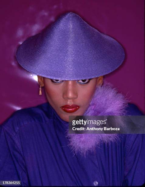 Portrait of American fashion model Toukie Smith as she poses, dressed in purple, with a matching, conical hat, New York, New York, early 1980s.