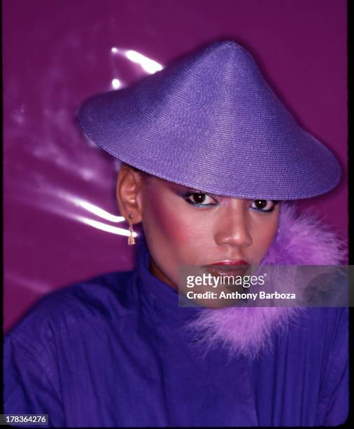 Portrait of American fashion model Toukie Smith as she poses, dressed in purple, with a matching, conical hat, New York, New York, early 1980s.