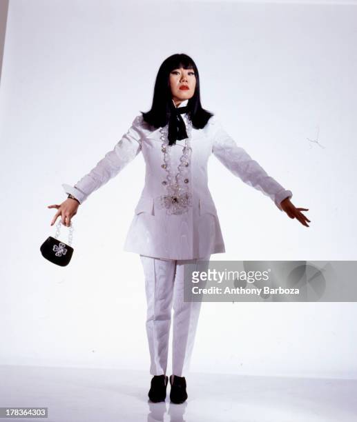 Portrait of American fashion designer Anna Sui as she poses, dressed in a white suit, against a white background in a studio, New York, New York,...