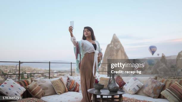 young female tourist taking selfies wither her mobile smart phone in cave hotel in cappadocia during her travel - göreme national park stock pictures, royalty-free photos & images