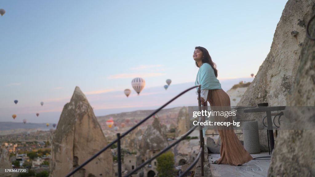 Porträt einer jungen Touristin, die während ihrer Reise Heißluftballons vom Balkon in Kappadokien aus beobachtet