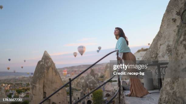 porträt einer jungen touristin, die während ihrer reise heißluftballons vom balkon in kappadokien aus beobachtet - göreme stock-fotos und bilder