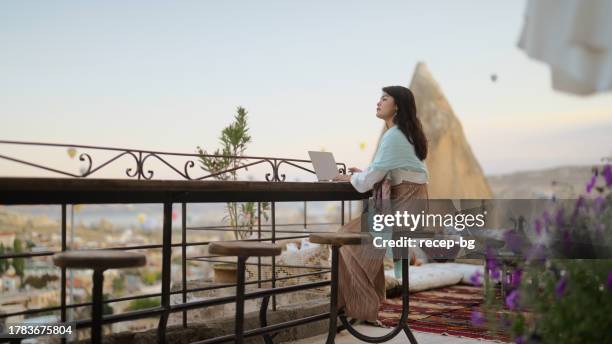 beautiful young woman using laptop in cave hotel during her travel - wonderlust computer stock pictures, royalty-free photos & images