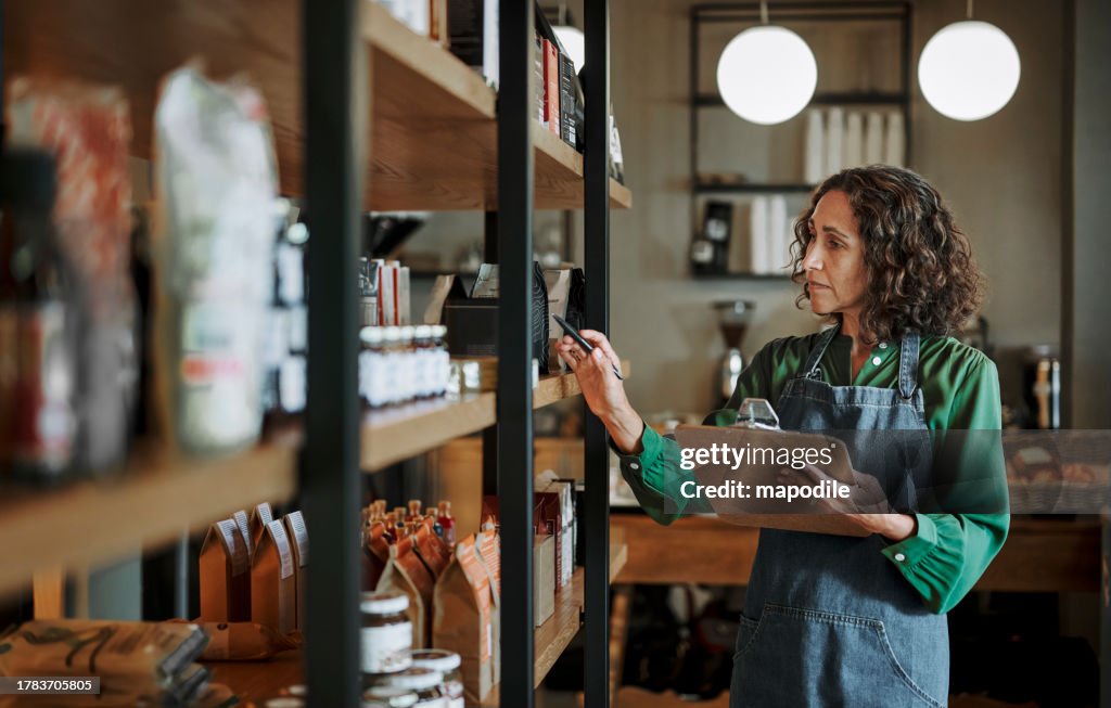 Mature deli owner taking inventory on store shelves using a clipboard