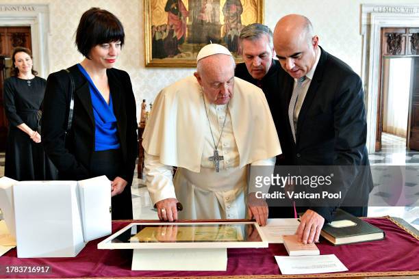 Pope Francis exchanges gifts with the president of the Swiss Confederation Alain Berset and his wife Muriel Zeender during an audience at the...