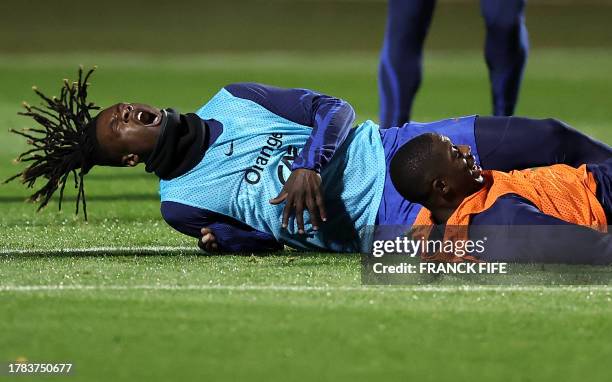 France's midfielder Eduardo Camavinga reacts after a tackle by France's forward Ousmane Dembele during a training session in...