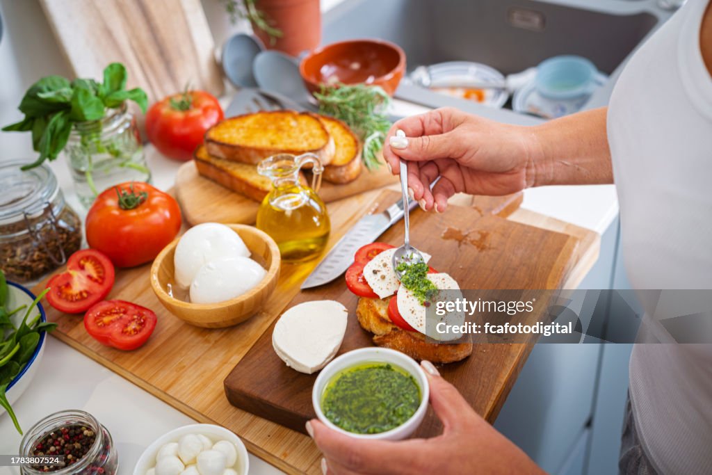 Close up of wwoman hands dressing fresh Caprese salad on a toasted bread