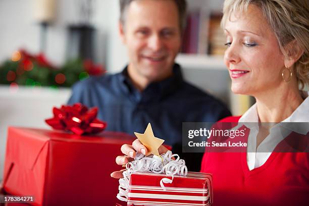 woman reads gift tag on christmas gift - gift tag and christmas stockfoto's en -beelden