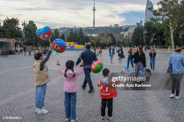 Children hold balloons as flags in Baku Boulevard on November 9, 2023 in Baku, Azerbaijan. The three-color flag with a crescent and an eight-pointed...