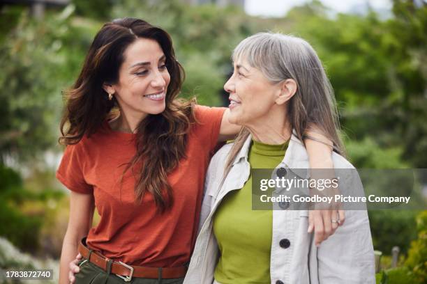 smiling woman talking with her senior mom while walking outside - förälder bildbanksfoton och bilder