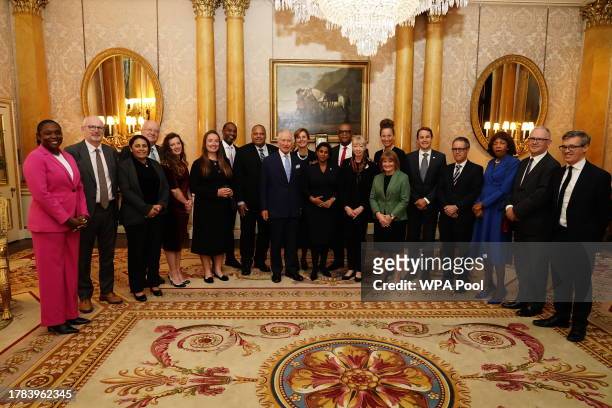 King Charles III smiles as he poses for a photo during a reception for delegates of the Overseas Territories Ministerial Council during at Buckingham...