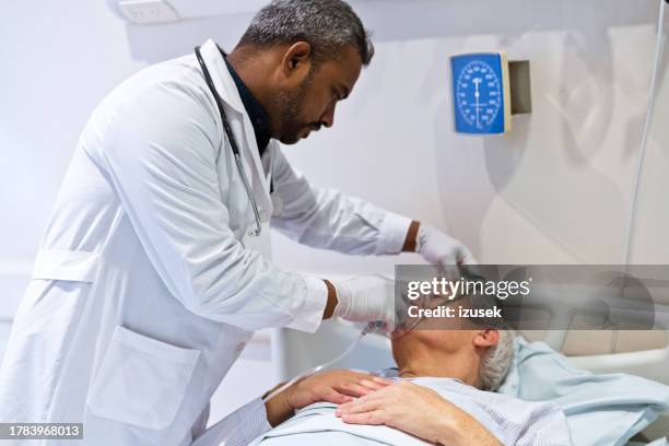 mitarbeiter des gesundheitswesens, der dem patienten eine sauerstoffmaske gibt - atemhilfe stock-fotos und bilder