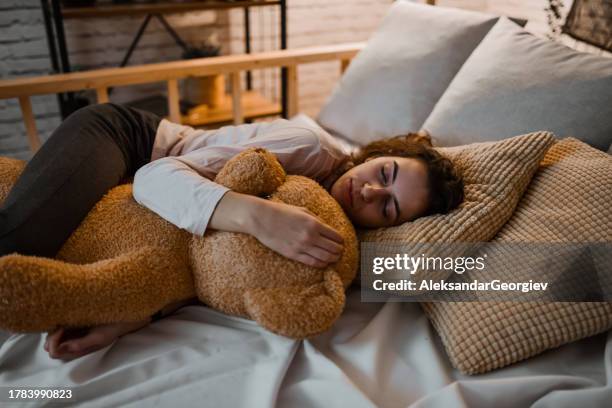female enjoying the warmth of teddy bear while falling asleep - stuffed toy stock pictures, royalty-free photos & images