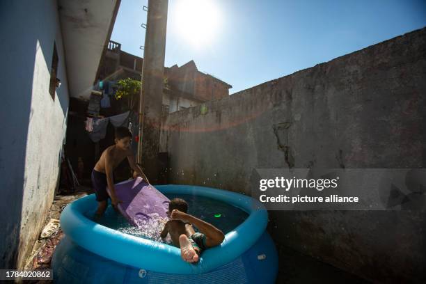 November 2023, Brazil, Sao Paulo: Children play in a small pool of water in a hallway during an extreme heatwave. Even before the start of summer in...