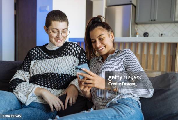 teenager girls using mobile phone at home. two young woman using image based mobile apps on smart phones - image based social media stock pictures, royalty-free photos & images