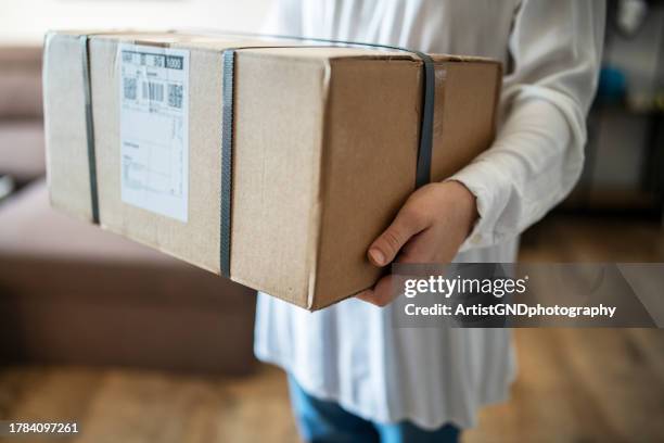 woman holding a big parcel just delivered to her home. - parcel delivery stock pictures, royalty-free photos & images