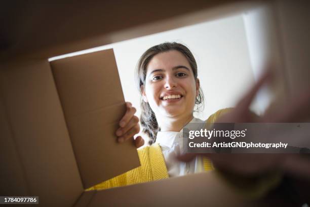 shot from below of woman opening a parcel from online shopping. - opening package stock pictures, royalty-free photos & images