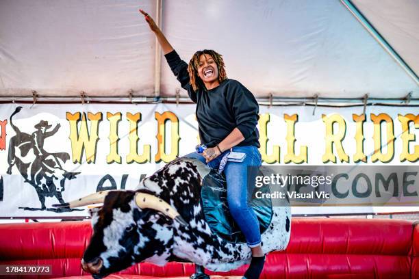 woman riding mechanical bull - mechanical bull woman stock pictures, royalty-free photos & images