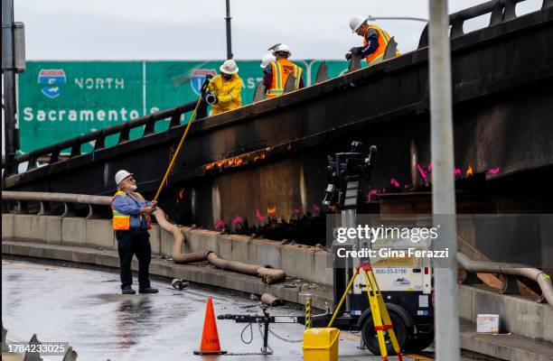 Construction workers take measurements along the burned portion of the 10 freeway above 14th Street at Alameda on November 15, 2023 in Los Angeles,...
