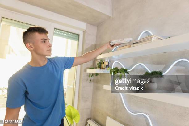 adolescente che fa le faccende domestiche - organizzare i libri - spolverare foto e immagini stock