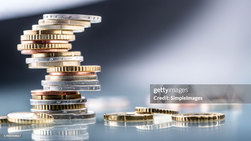 Euro coins built in the shape of a tower that balances before falling, a symbol of financial growth and fall - Close Up.