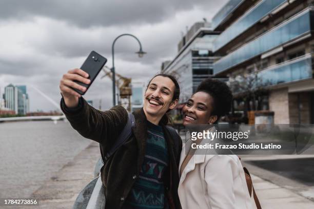 young couple taking a selfie in puerto madero, buenos aires - puerto stock pictures, royalty-free photos & images