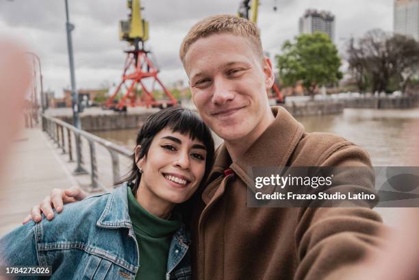 young couple taking a selfie in puerto madero, buenos aires - camera point of view - puerto stock pictures, royalty-free photos & images