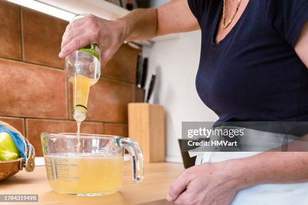 mature woman in domestic kitchen preparing pepper for making homemade vegetable preserves - vinegar stockfoto's en -beelden