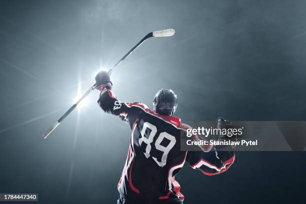 hockey player rejoicing in victory while lifting the hockey stick against lights and dark backround - giocatore di hockey foto e immagini stock