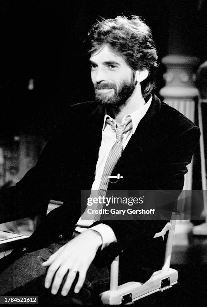 View of American Pop musician Kenny Loggins, sitting in a director's chair, during an interview on MTV at Teletronic Studio, New York, New York,...