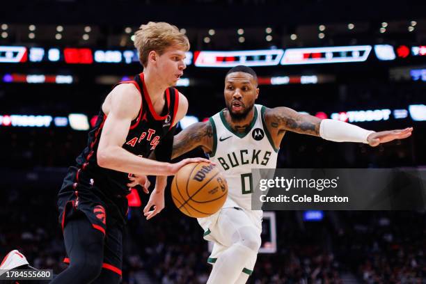 Gradey Dick of the Toronto Raptors is defended by Damian Lillard of the Milwaukee Bucks as he dribbles during the first half of their NBA game at...