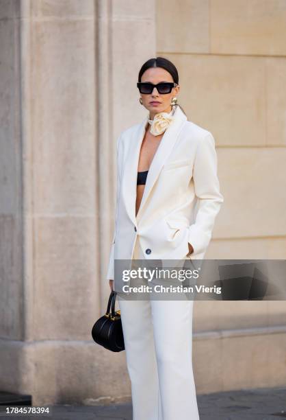 Zina Charkoplia wears white suit by MyBestFriends, black pointed boots Blanc sur Blanc, black Dior bag, Arket flower choker on November 09, 2023 in...