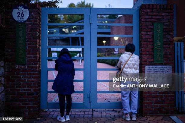 Relatives stand outside the school gates after dropping their children to sit for the annual college entrance exam, known locally as Suneung, outside...