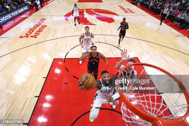 Damian Lillard of the Milwaukee Bucks drives to the net with Jakob Poeltl and Scottie Barnes of the Toronto Raptors trailing behind during the first...