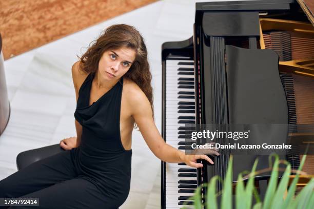 young woman playing piano while sitting on bench - morning sickness stockfoto's en -beelden