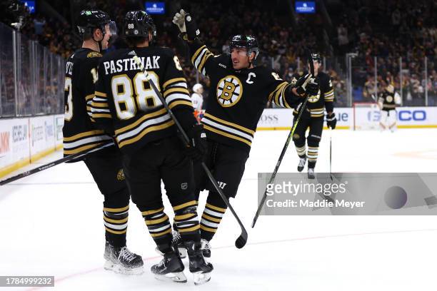 Charlie Coyle of the Boston Bruins celebrates with David Pastrnak and Brad Marchand after scoring a hat trick during the third period against the New...