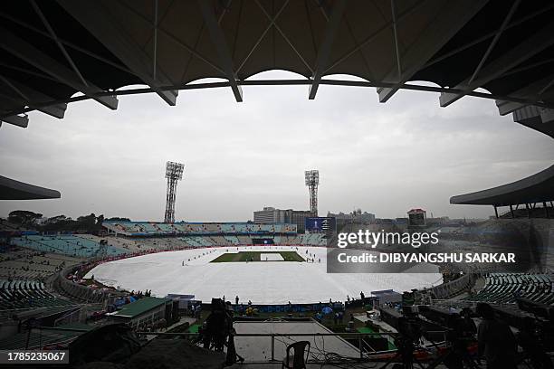 Ground staff remove the rain covers from the pitch before the start of the 2023 ICC Men's Cricket World Cup one-day international second semi-final...