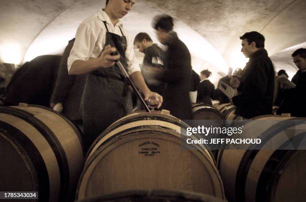 Un caviste prélève du vin d'un fût avant de servir un verre, le 18 novembre 2007 dans une cave des Hospices de Beaune, lors d'une dégustation ouverte...