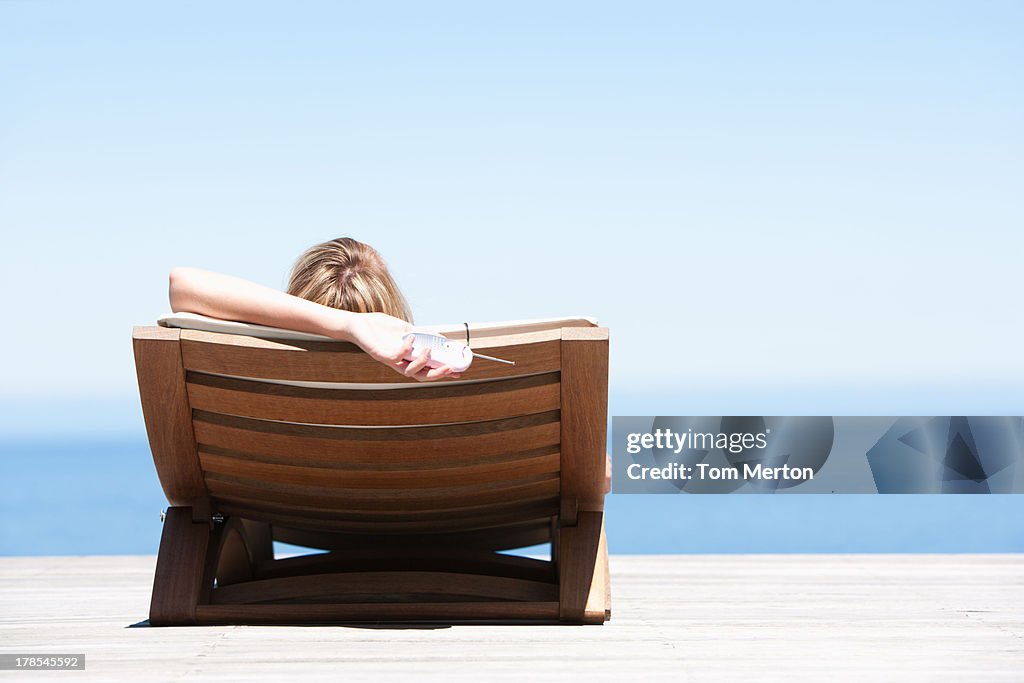 Rear view of woman reclining on folding chair outdoors