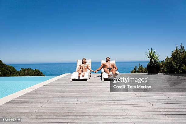 homme et femme de chaises longues sur la terrasse prendre un bain de soleil en tenant les mains - eau dormante photos et images de collection