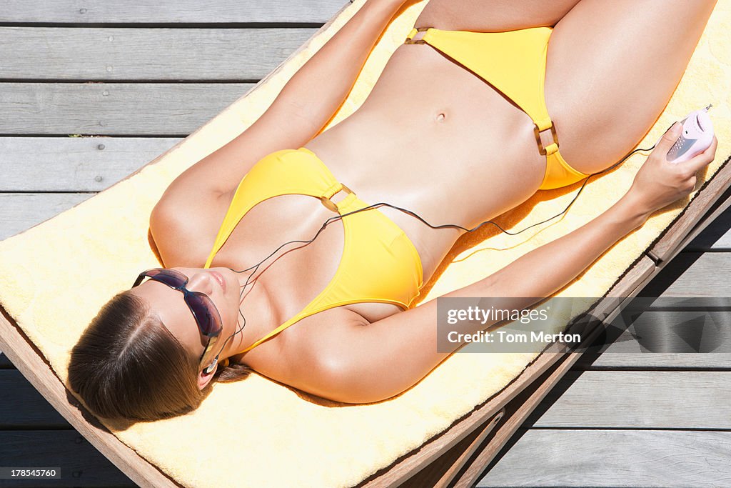 Femme au soleil sur une chaise pliante, écouter de la musique