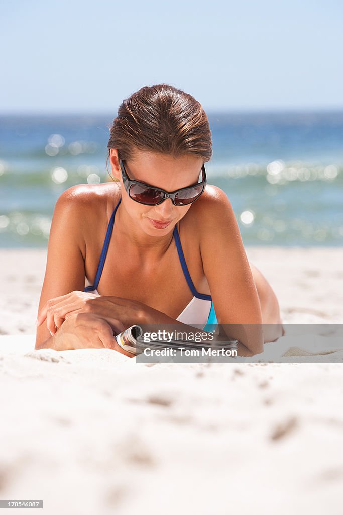 Woman lying down at beach with reading book