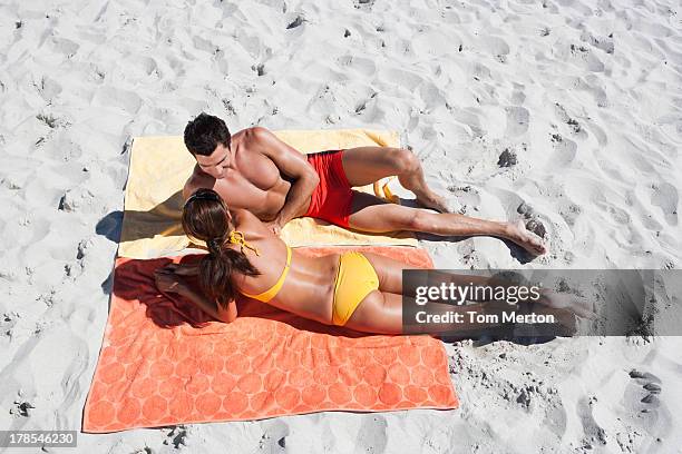 uomo e una donna prendere il sole su asciugamani da spiaggia in sabbia - telo da mare foto e immagini stock