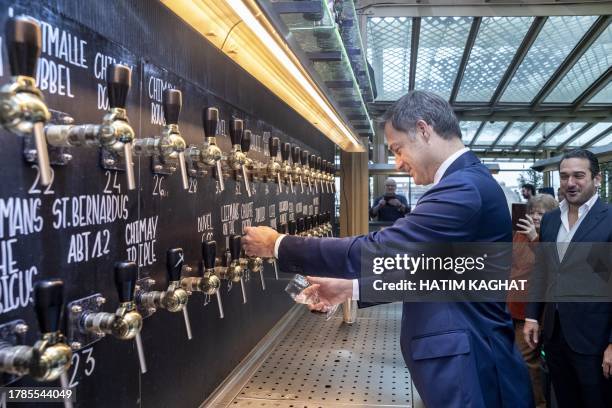 Belgium's Prime Minister Alexander De Croo pours a beer from a multi tap next to CEO of Belgian Brewers Krishan Maudgal during the launch of a new...